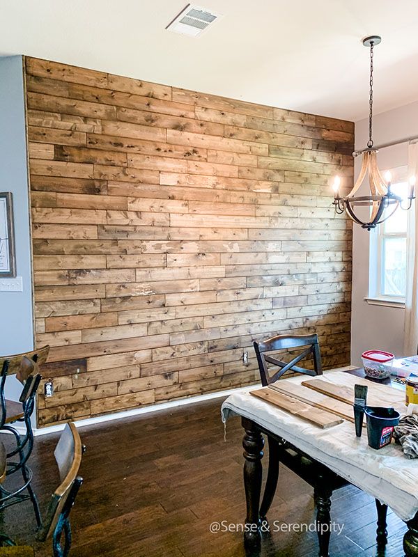 a dining room table and chairs in front of a wooden wall with wood planks