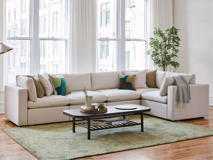 a living room with white couches and green rugs in front of large windows