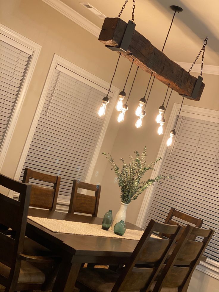 a dining room table and chairs with lights hanging from the ceiling