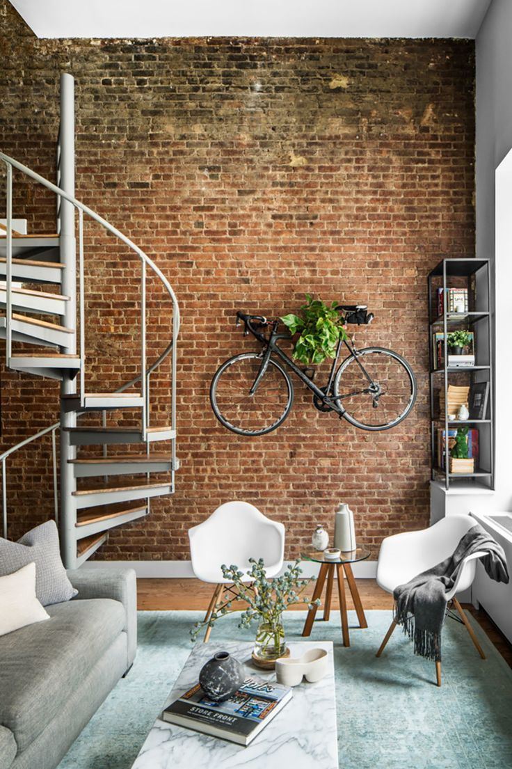 a living room filled with furniture and a bike mounted to the wall next to a spiral staircase