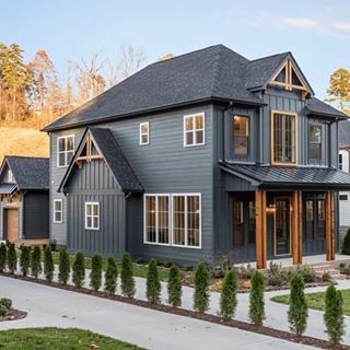 a large gray house with lots of windows on the front and side of it's roof