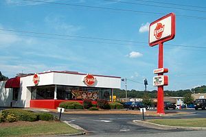 a fast food restaurant with a red and white sign next to it's entrance