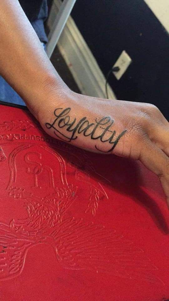 a person with a tattoo on their arm holding onto a red table and the word joy written in cursive writing