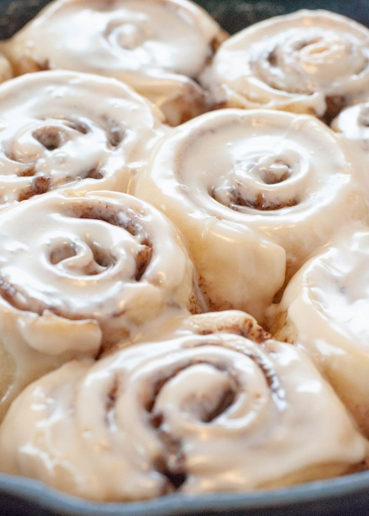 a pan filled with cinnamon rolls covered in icing