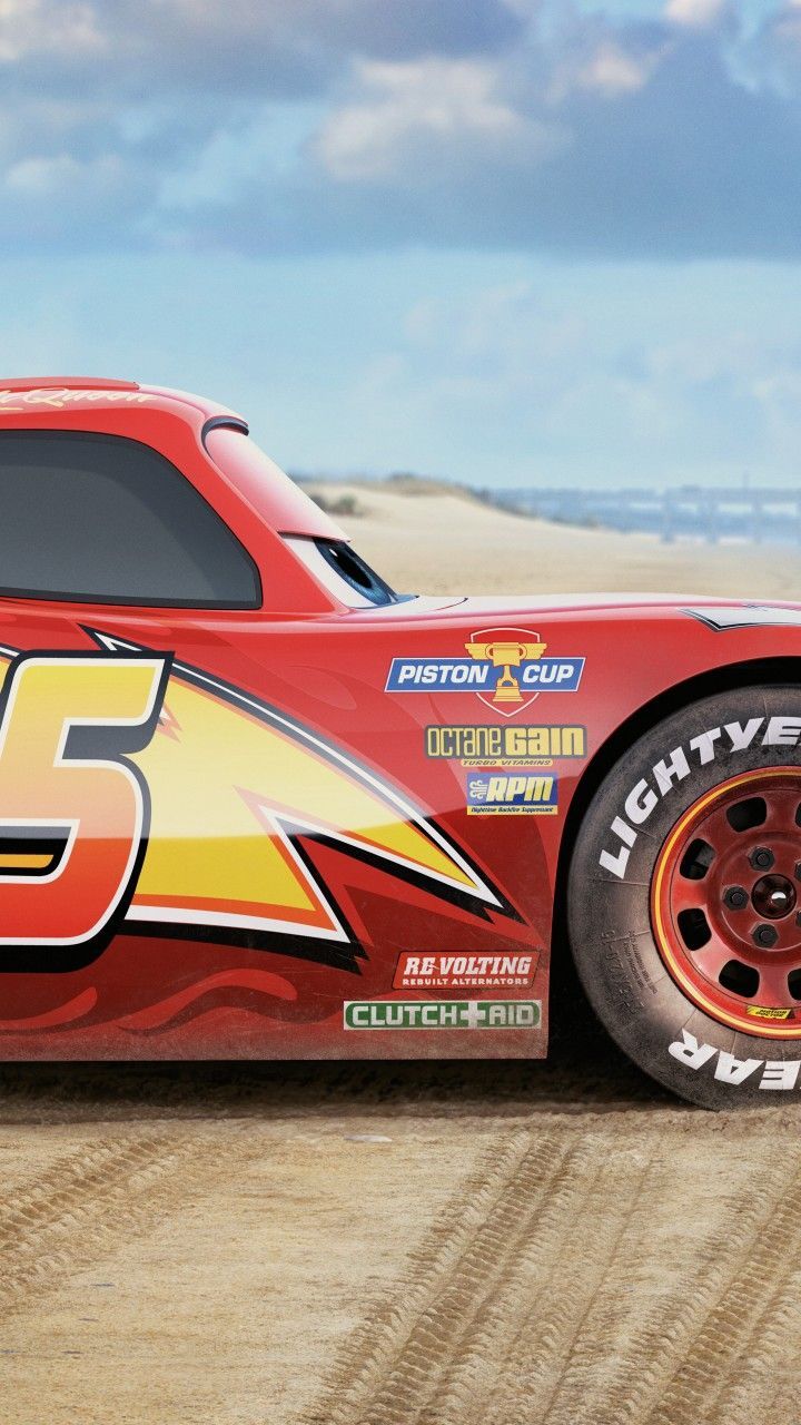 a red race car with flames on it's side in the sand and blue sky