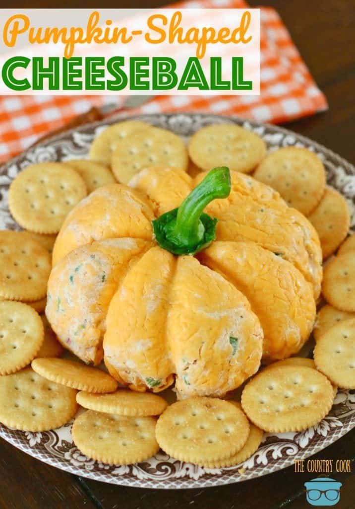 pumpkin shaped cheeseball on a plate with crackers