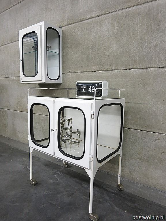 two white cabinets sitting next to each other on the side of a building with windows