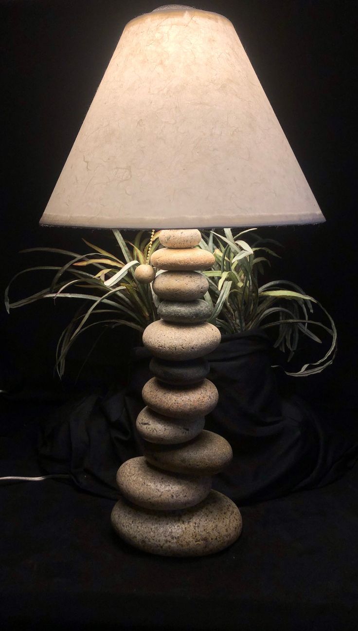 a lamp that is sitting on top of some rocks and has plants growing out of it