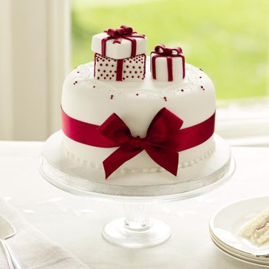 a white cake with red ribbon and presents on top