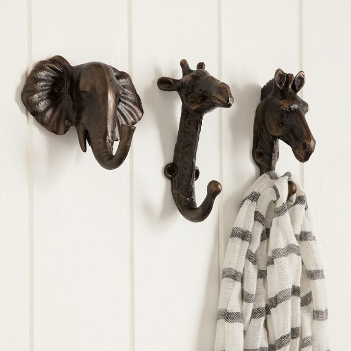 two giraffe head hooks on the wall next to towels hanging from hooks and towel holders