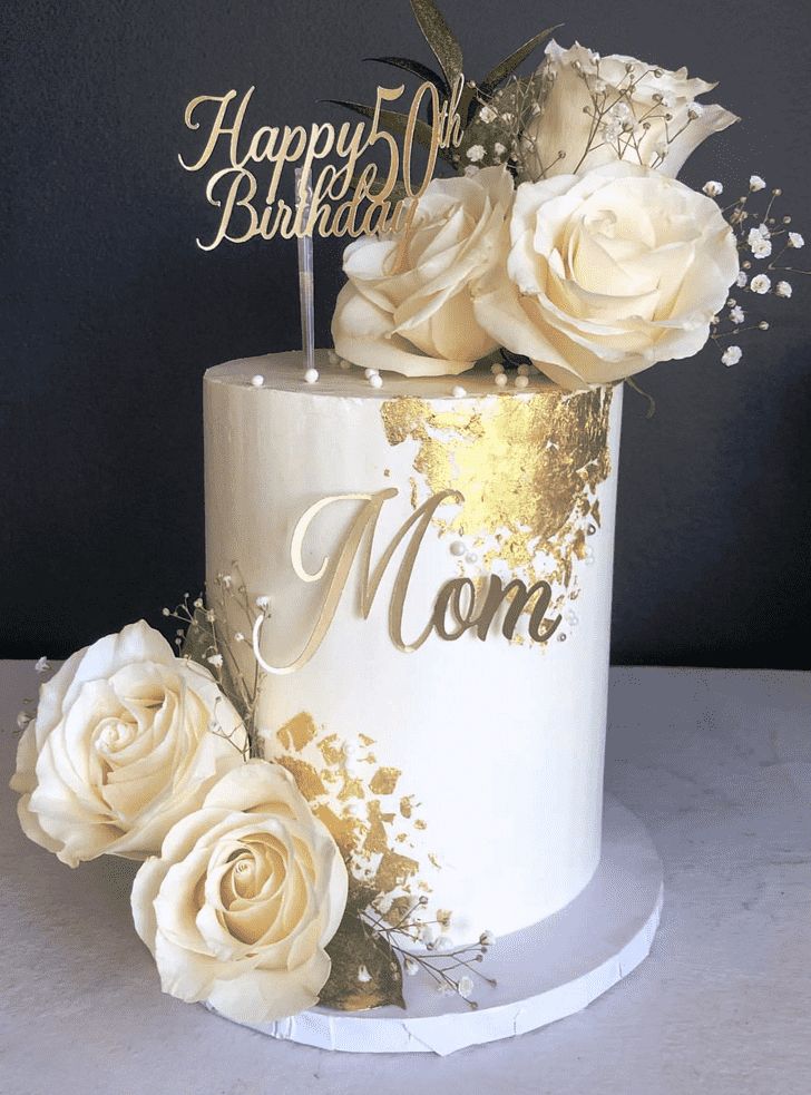 a white and gold birthday cake with flowers on top