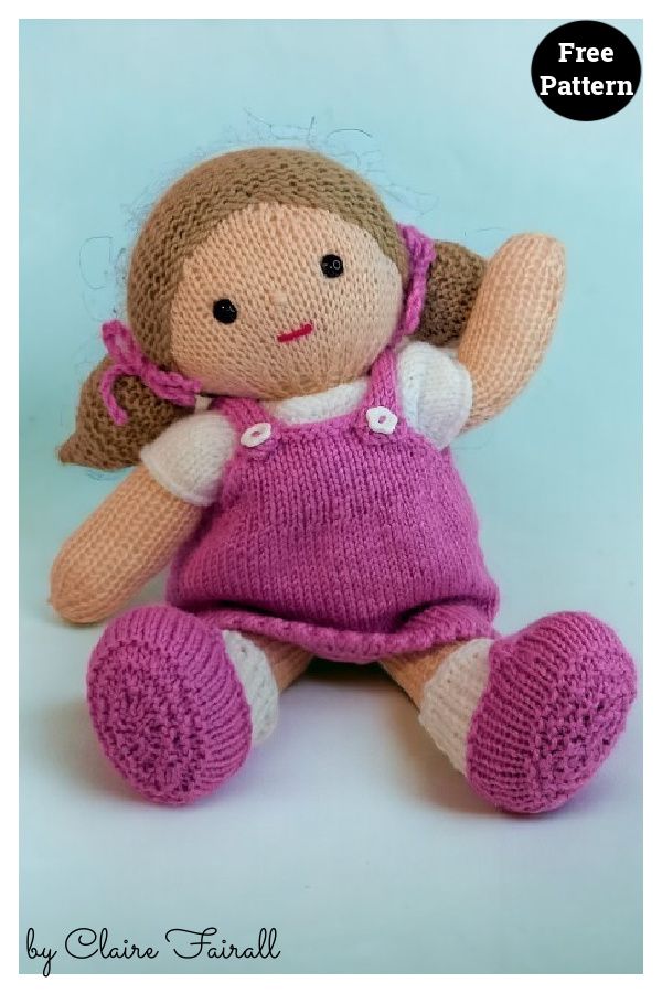 a knitted doll sitting on the ground with its legs crossed and one hand in the air