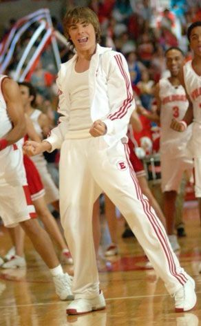 young men in white and red uniforms on a basketball court with people watching from the sidelines