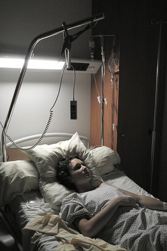 a person laying in a hospital bed under a lamp