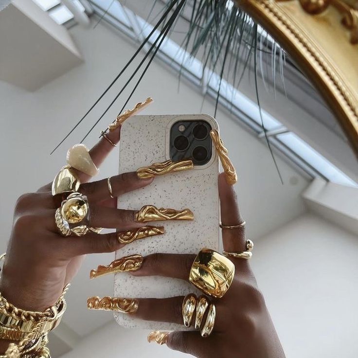 a woman holding up her phone case with gold rings on it and one hand in the air