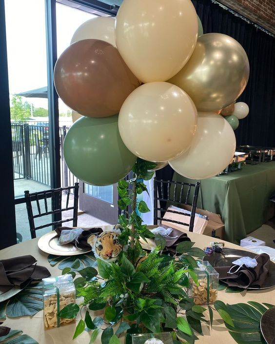 a table topped with lots of balloons and greenery