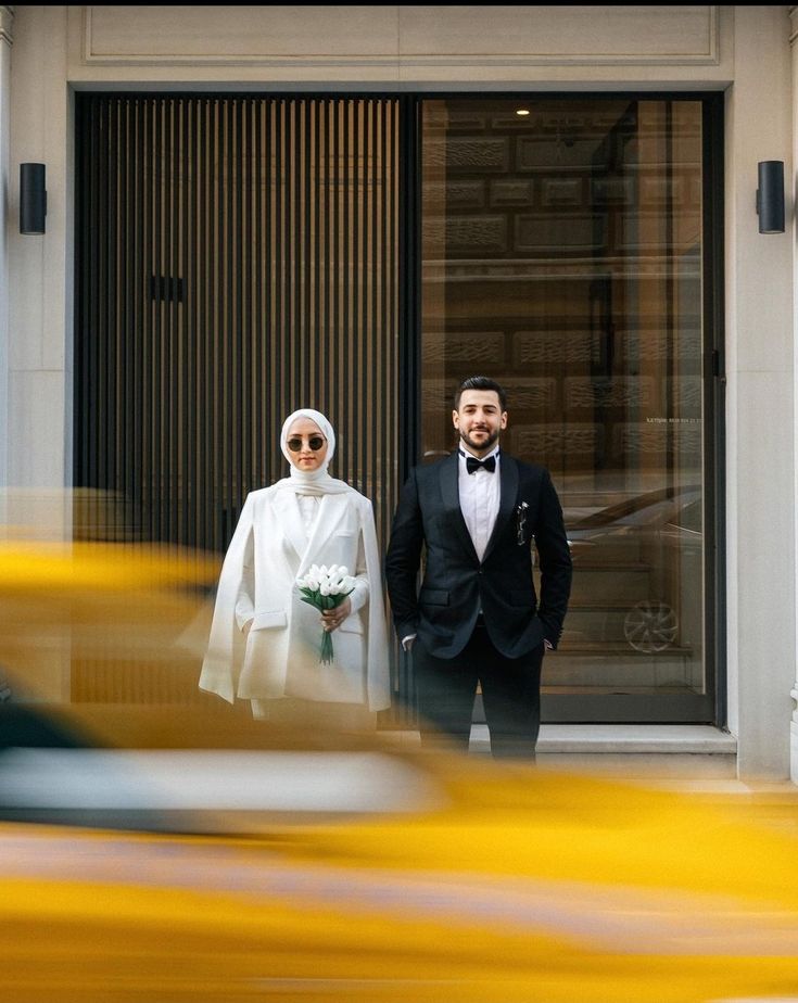 a man and woman dressed in formal wear standing next to each other on the street