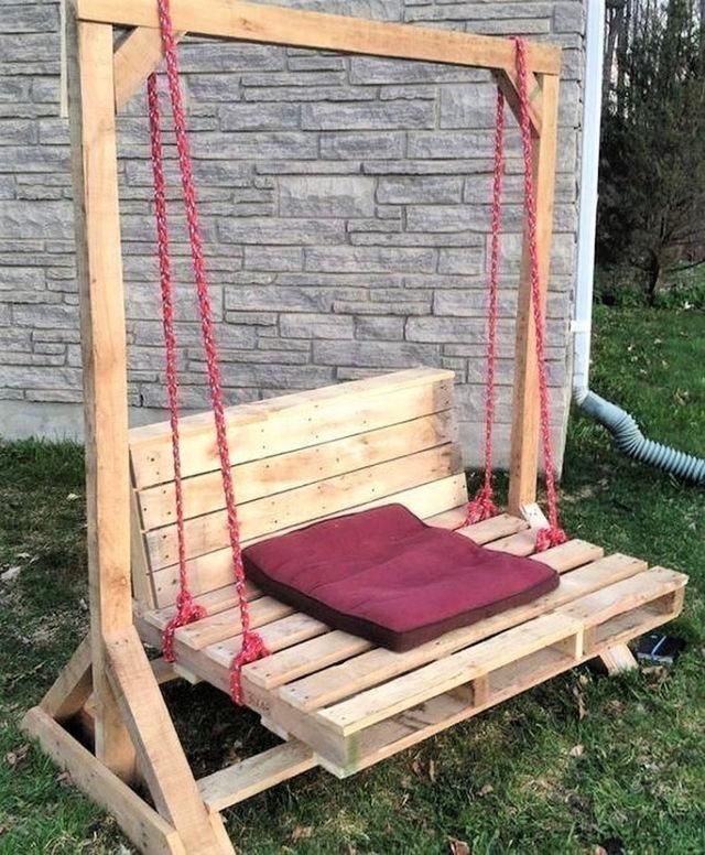 a swing bed made out of pallet wood with a pillow on it and rope