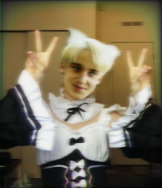 a person with blonde hair making the peace sign in front of her face and wearing a black and white outfit