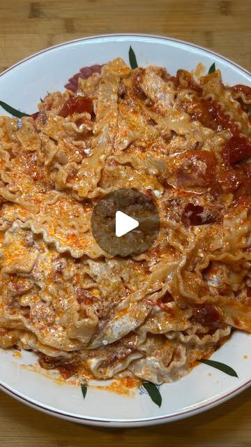 a white plate topped with pasta and meat covered in sauces on top of a wooden table