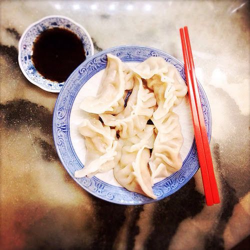 dumplings and chopsticks on a plate with sauce in the bowl next to them