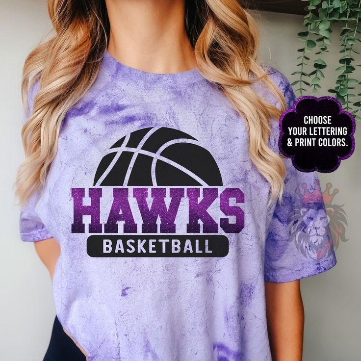 a woman wearing a purple shirt with the words hawks basketball on it