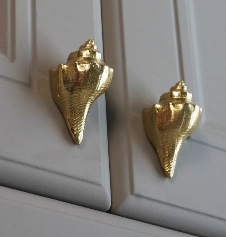 two gold earrings sitting on top of a white cabinet