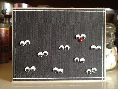 a black card with white eyes and red noseballs on it, sitting on a table