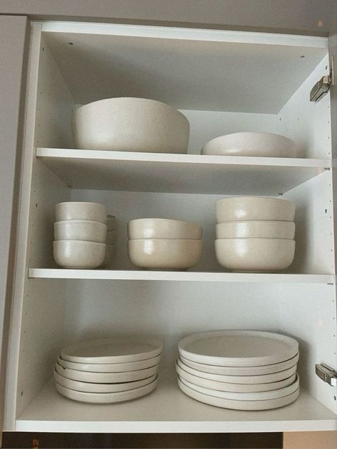 white dishes are stacked on top of each other in a cupboard with plates and bowls