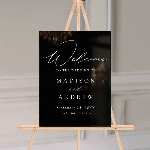 a black and white wedding welcome sign hanging from a wooden easel