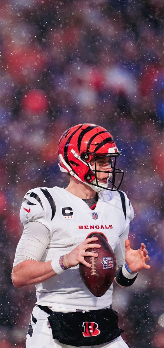 a football player holding a ball on top of a snow covered field in the rain