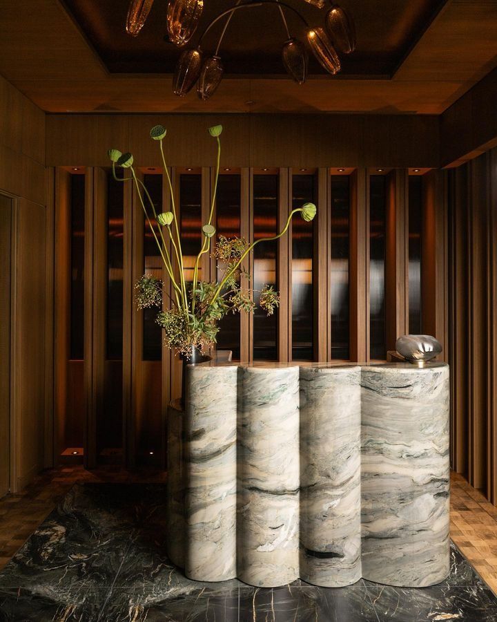 three vases with flowers in them sitting on a marble floor next to a wall