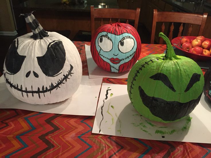 three decorated pumpkins sitting on top of a table