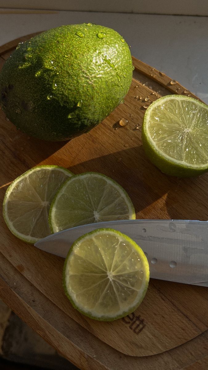 a cutting board with limes and a knife on it