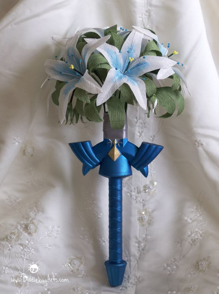 a blue and white flower bouquet on top of a metal pole with ribbon around it