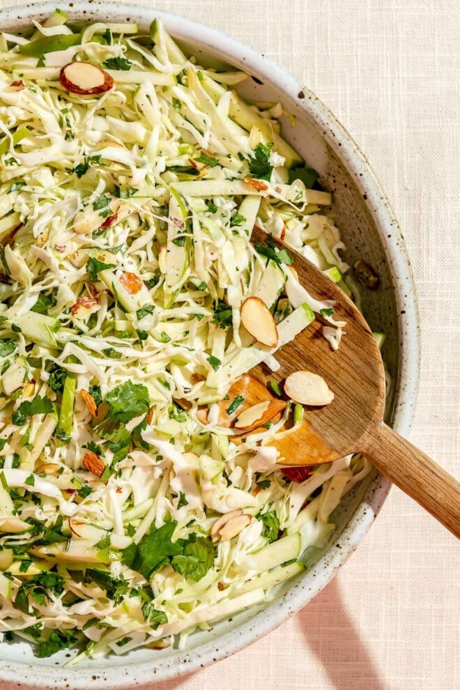 a white bowl filled with coleslaw and almonds