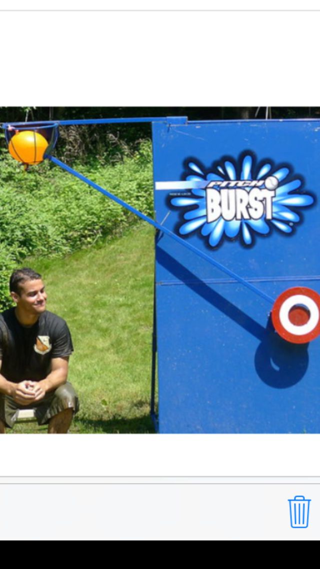 a man sitting on the ground in front of a blue box with an orange ball hanging from it