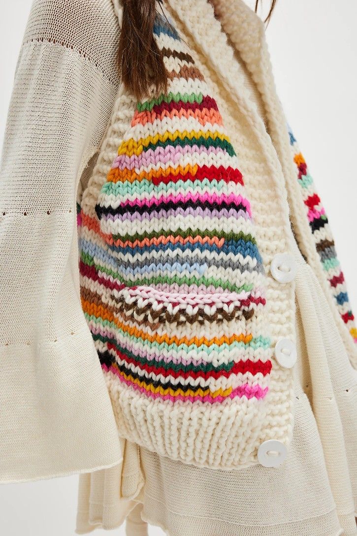 a woman wearing a white sweater with multicolored stripes on the sleeves and back