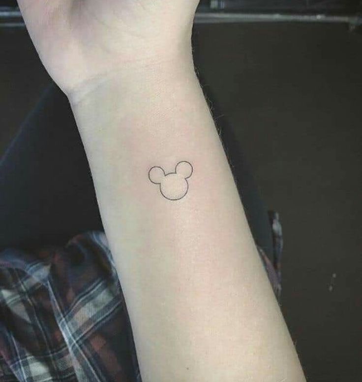 a small wrist tattoo with a mickey mouse head on it's left arm,