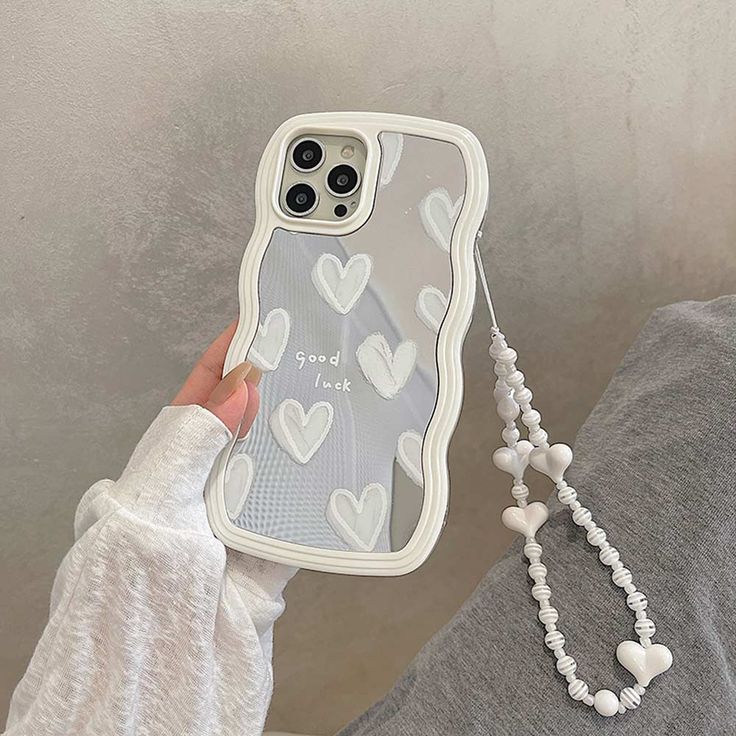 a person holding up a phone case with hearts on it and a chain attached to the back