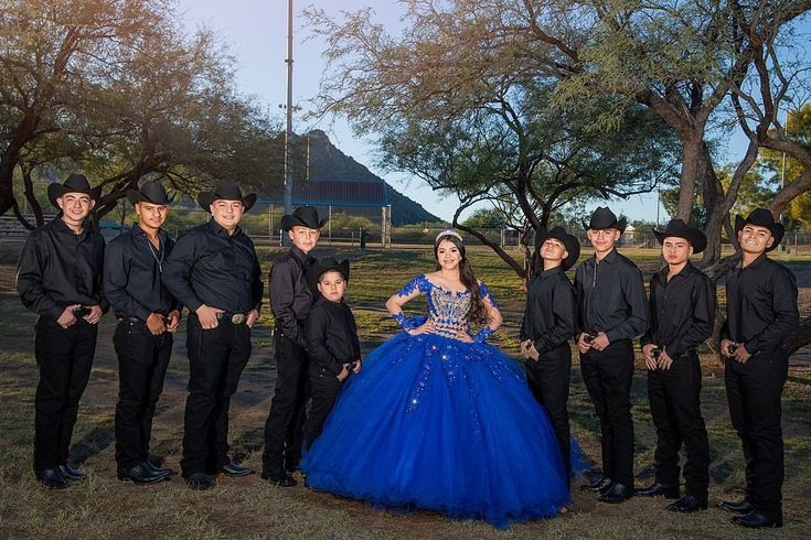 a group of people standing next to each other wearing black suits and blue gowns