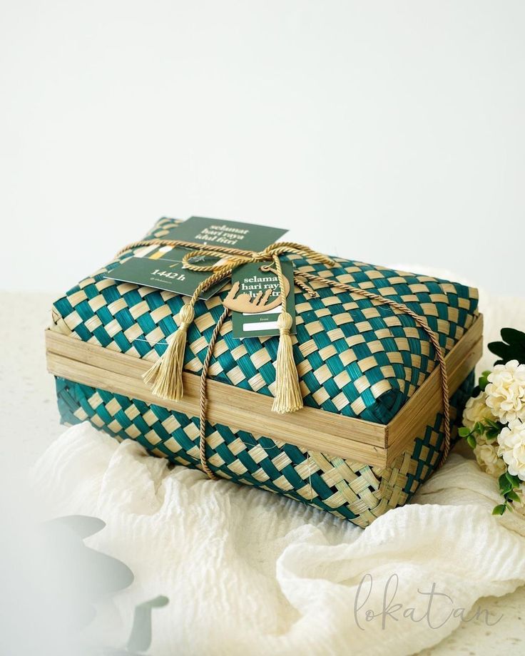 a green and white box sitting on top of a table next to flowers in vases