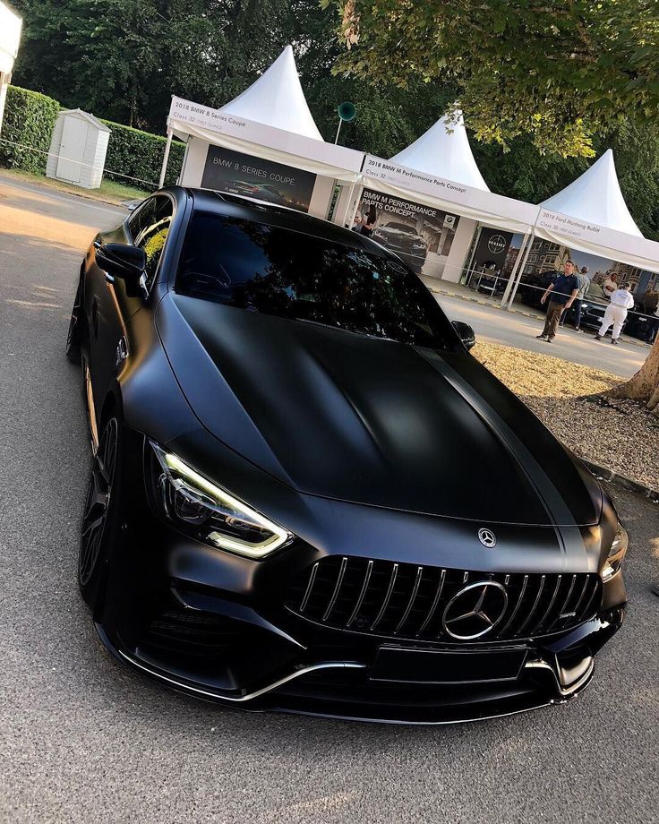 a black sports car parked in front of some tents