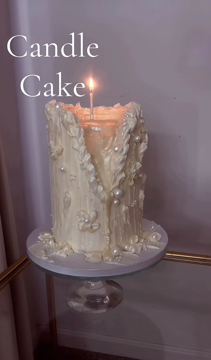 there is a candle that is on top of a cake with pearls and icing