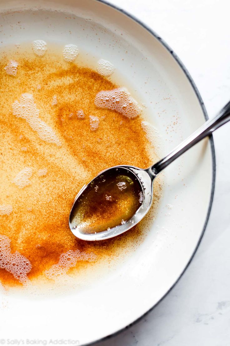 a white bowl filled with liquid and a spoon