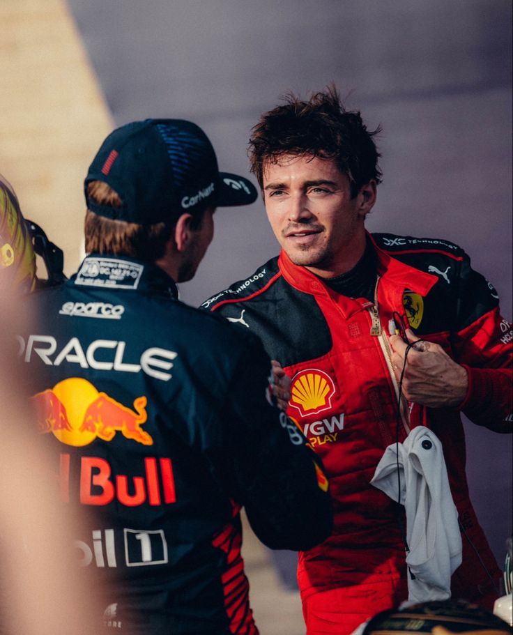 two men talking to each other in front of a wall with the words red bull written on it