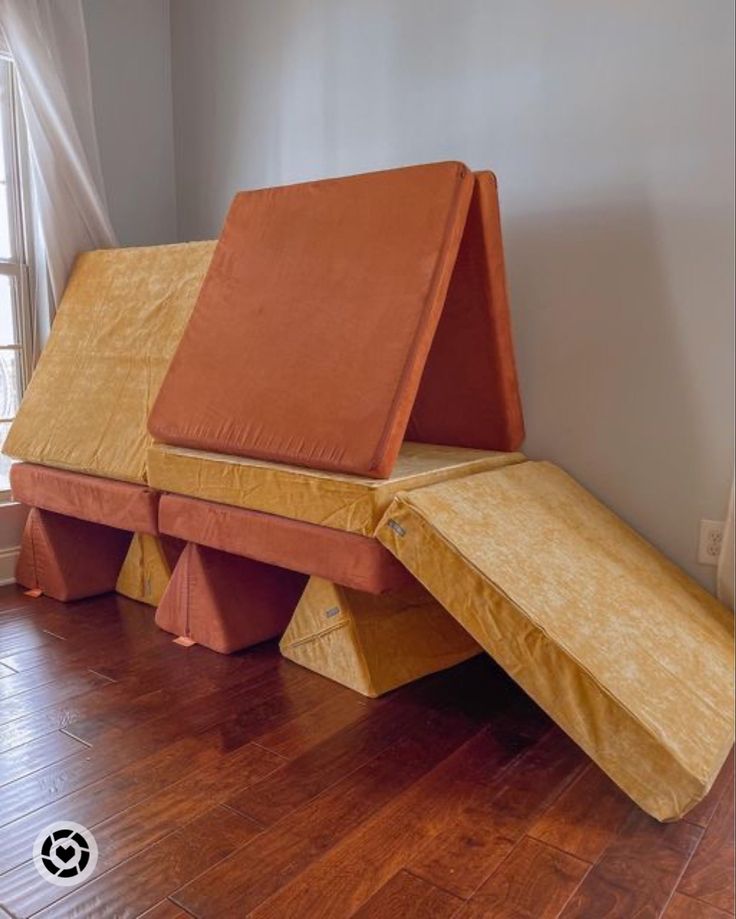 two orange benches sitting on top of a hard wood floor in front of a window