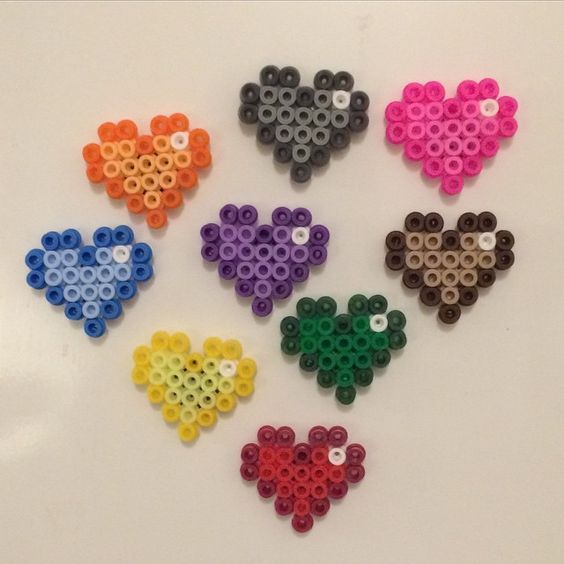 six different colored heart shaped beads on a white surface