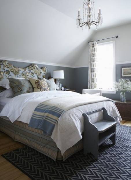 a bed room with a neatly made bed and a chandelier hanging from the ceiling