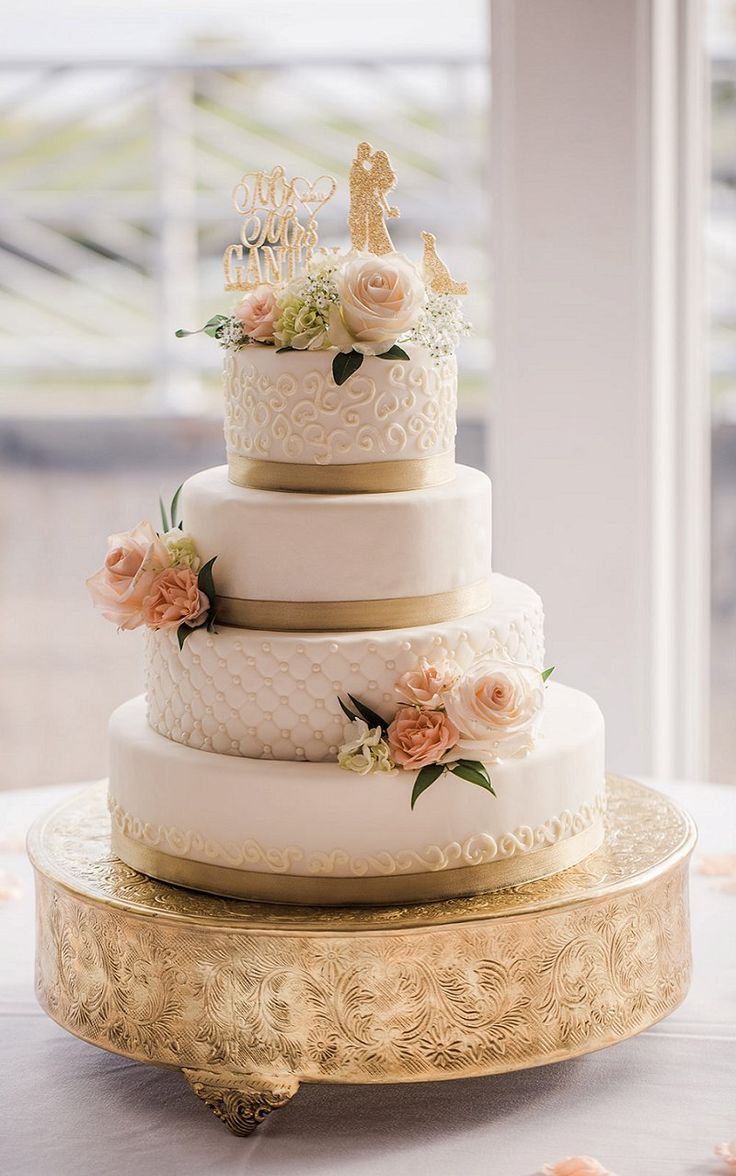 a three tiered wedding cake sitting on top of a gold platter with flowers